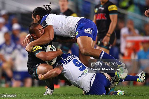 Sika Manu of the Panthers is tackled by Martin Taupau of the Bulldogs during the round 25 NRL match between the Canterbury Bulldogs and the Penrith...