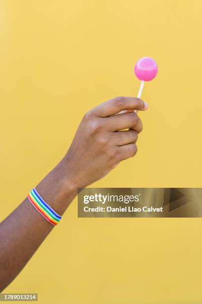 person with a rainbow bracelet holding a lollipop. - black woman holding food stock pictures, royalty-free photos & images