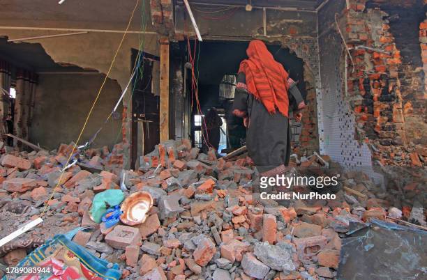 Woman walks on the debris of a house at the site of gun-battle in Samnu village in Kulgam district on November 17, 2023. Five militants were killed...