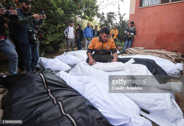 Palestinian man mourns arund the dead bodies in body bags at Nasser Hospital, where the bodies of those who lost their lives in Israeli attacks were...