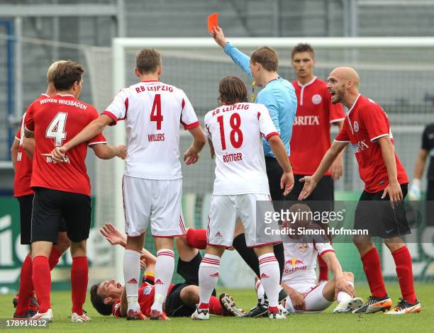 Referee Martin Petersen shows the red card to Michael Wiemann of Wiesbaden during the Third Bundesliga match between SV Wehen Wiesbaden and...