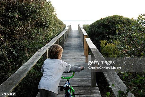boy pushing bike down boardwalk - hilton head photos et images de collection