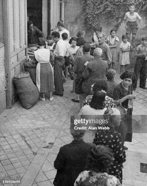 Faced with a food shortage due to the Spanish Civil War, people line up for food at a distribution centre where rations are issued at 7 a.m. Every...