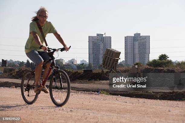 An Israeli man rides his bicycle past the 'Iron Dome' missile defense system as it is deployed on August 31, 2013 in Tel Aviv, Israel. Tensions are...