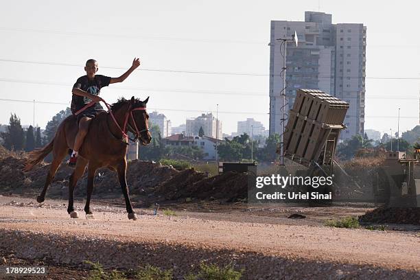 An Israeli youth ride his horse past the 'Iron Dome' missile defense system as it is deployed on August 31, 2013 in Tel Aviv, Israel. Tensions are...