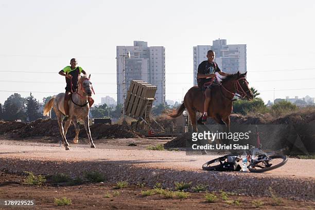 Israelis ride their horses past the 'Iron Dome' missile defense system as it is guarded by Israeli soldiers on August 31, 2013 in Tel Aviv, Israel....