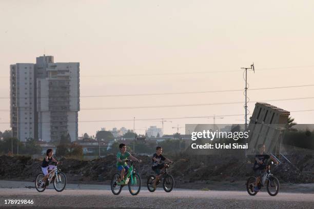 Israeli children ride their bicycle past the 'Iron Dome' missile defense system as it is deployed on August 31, 2013 in Tel Aviv, Israel. Tensions...