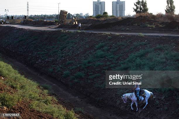 An Israeli man rides his horse past the 'Iron Dome' missile defense system as it is deployed on August 31, 2013 in Tel Aviv, Israel. Tensions are...