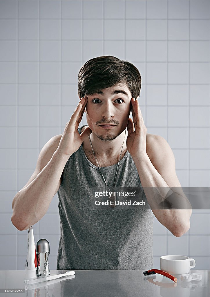 Young man looking into bathroom mirror
