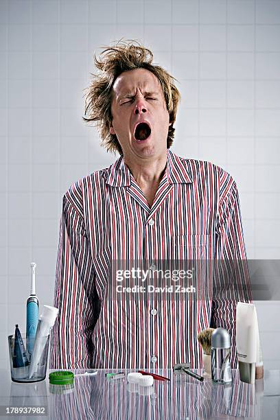 young man in pajamas yawning - gapen stockfoto's en -beelden