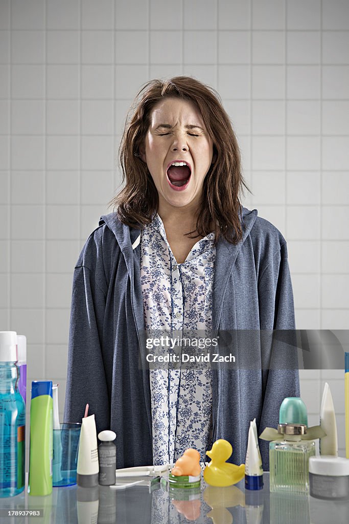 Young woman in bathroom, yawning