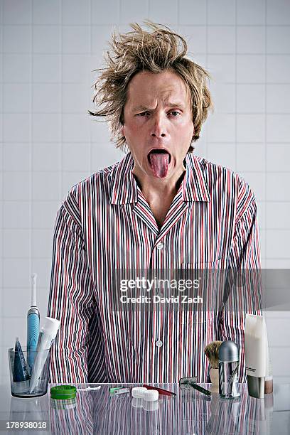 young man sticking tongue out. looking into mirror - tangled hair stock pictures, royalty-free photos & images