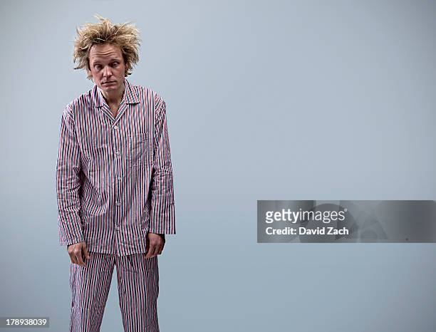 young man in pajamas looking tired, portrait - pajamas stock-fotos und bilder