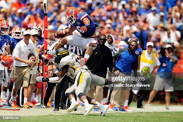 Trey Burton of the Florida Gators leaps over D.J. Larkins of the Toledo Rockets during a game at Ben Hill Griffin Stadium on August 31, 2013 in...