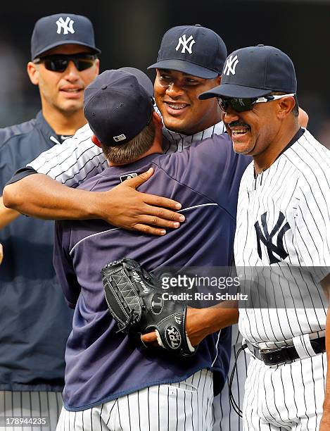 Pitcher Ivan Nova gets a hug from batting coach Kevin Long as pitcher Andy Pettitte and bench coach Tony Pena look on after Nova throw a complete...