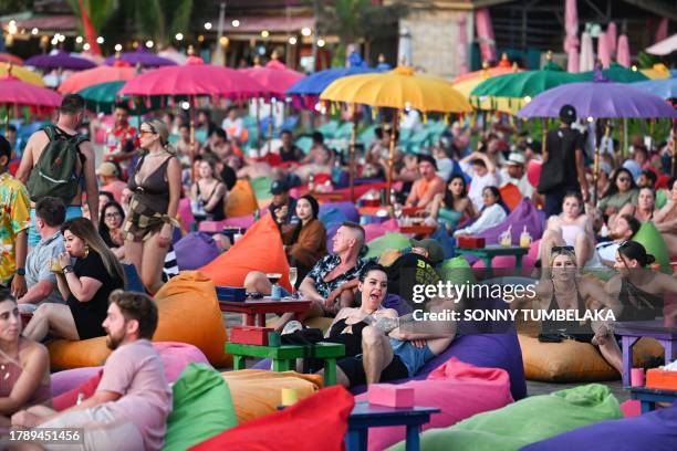 Foreign tourists relax on the Kuta Beach near Denpasar on Indonesia's resort island of Bali on November 18, 2023.