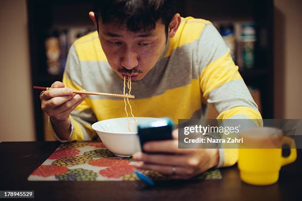 japanese man eating noodles while reading - noodles eating stock pictures, royalty-free photos & images