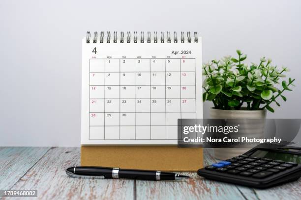 april 2024 desk calendar with calculator, pen and green potted plant - day of the week stockfoto's en -beelden