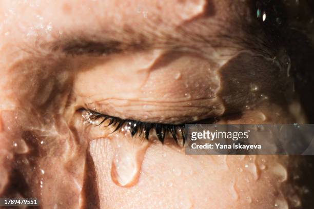 a beautiful and serene european woman is taking a shower, water flowing over her face. hygiene and self-care - water crisis stock pictures, royalty-free photos & images
