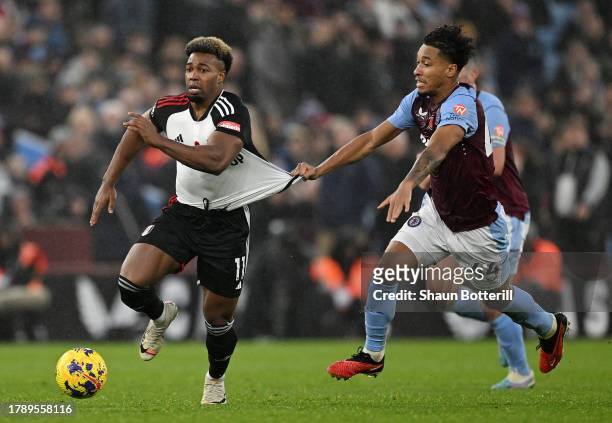 Adama Traore of Fulham runs with the ball whilst under pressure from Boubacar Kamara of Aston Villa during the Premier League match between Aston...