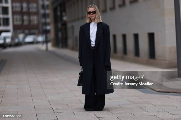 Isabelle Hartmann seen wearing Vehla Eyewear black sunglasses, COS silver earrings, Miu Miu white turtleneck shirt, Zara men dark blue wool long...