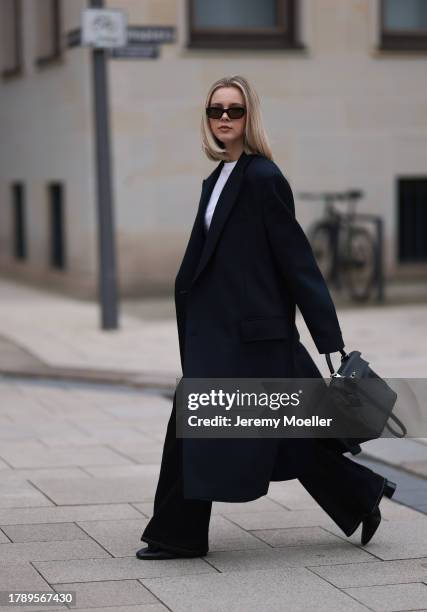 Isabelle Hartmann seen wearing Vehla Eyewear black sunglasses, COS silver earrings, Miu Miu white turtleneck shirt, Zara men dark blue wool long...