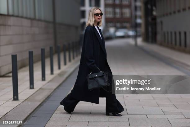 Isabelle Hartmann seen wearing Vehla Eyewear black sunglasses, COS silver earrings, Miu Miu white turtleneck shirt, Zara men dark blue wool long...