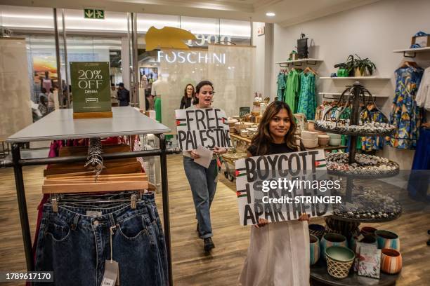 South African activists of the Boycott, Divestment and Sanctions hold banners with slogans in support of the Palestinian territories inside a shop as...