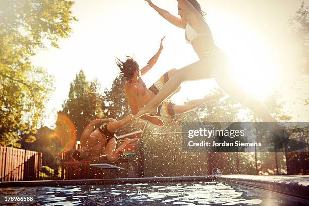 three friends enjoying a day at the pool. - jump in pool stock-fotos und bilder
