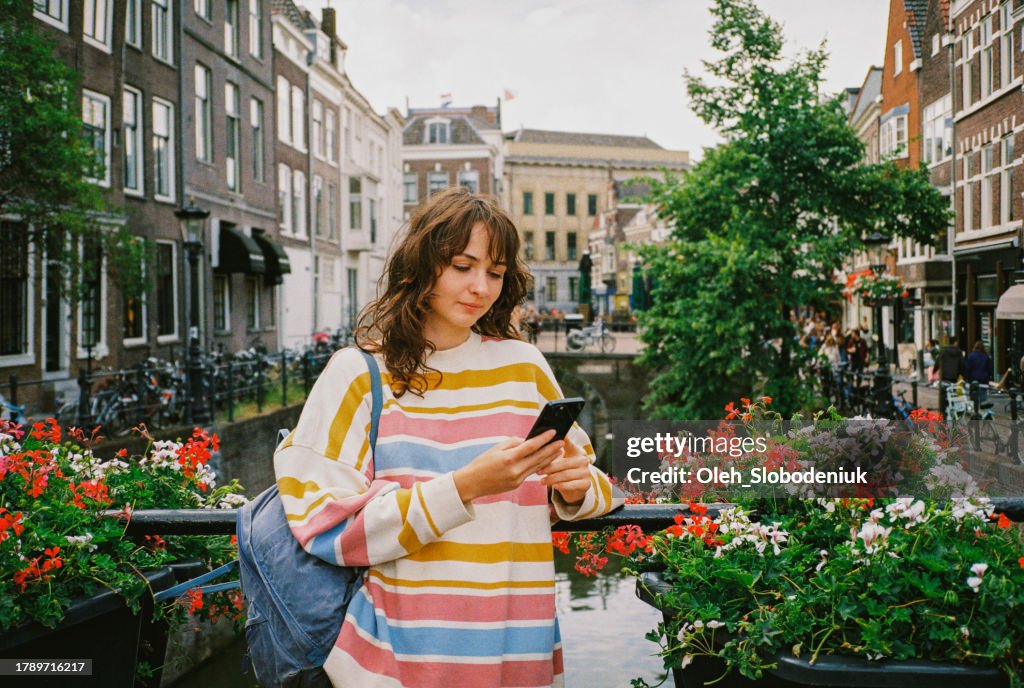 Woman standing in Utrecht in spring and using smartphone