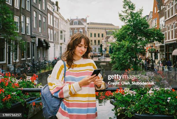 woman standing in utrecht in spring and using smartphone - amsterdam spring stock pictures, royalty-free photos & images