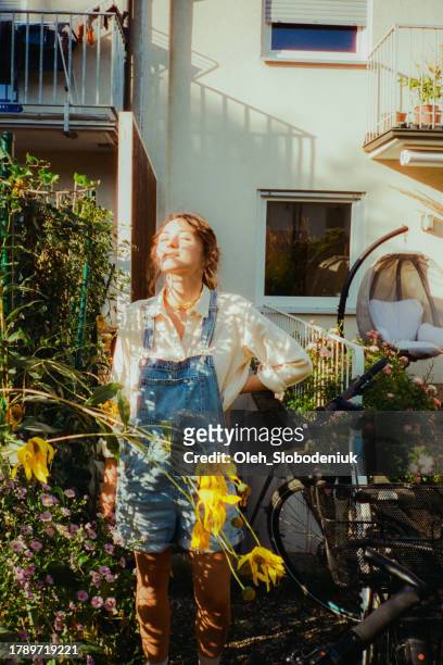 woman enjoying sunshine on the backyard while getting out bicycle from the basement - film darchive photos stock pictures, royalty-free photos & images