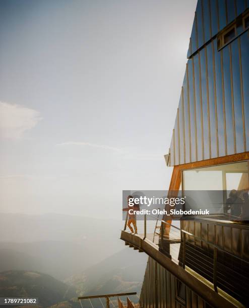 mujer de pie en el balcón de un refugio alpino moderno en los dolomitas - rambler house fotografías e imágenes de stock