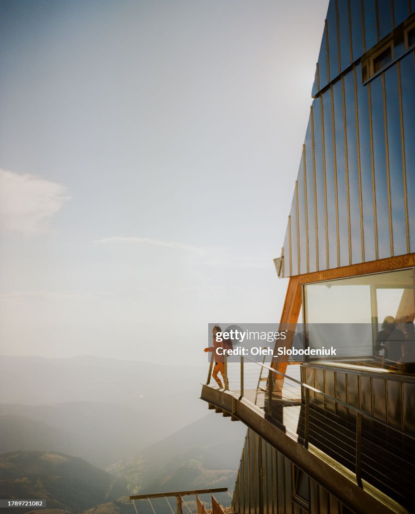 Woman standing at the balcony of modern alpine shelter in Dolomites