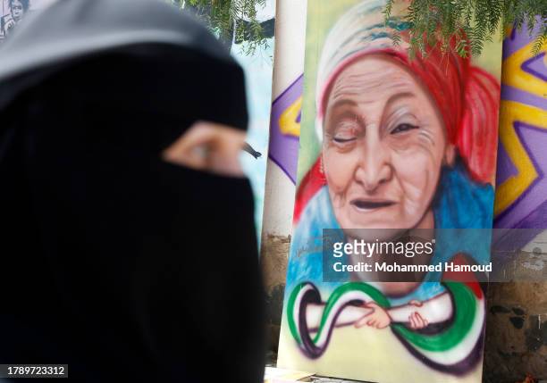 Yemeni woman walks near an artwork displayed in solidarity with Palestinians against the Israeli aerial attacks and ground invasion on the Gaza...