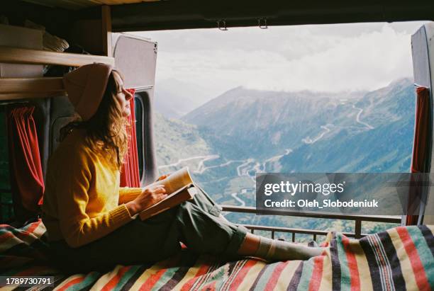 woman reading book in camper van during trip to swiss alps - mini van stock pictures, royalty-free photos & images