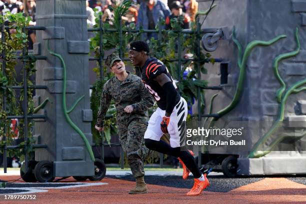 Cam Taylor-Britt of the Cincinnati Bengals runs onto the field with a service member before the game against the Houston Texans at Paycor Stadium on...