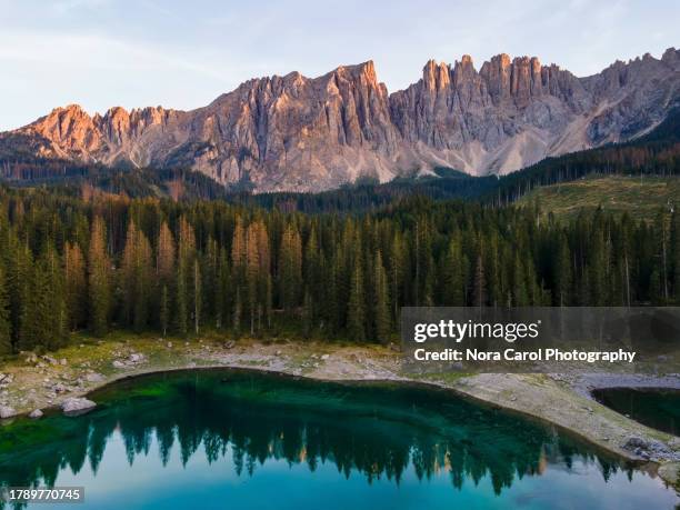 sunset over lake carezza karersee and latemar massif in dolomites - dolomiet stockfoto's en -beelden