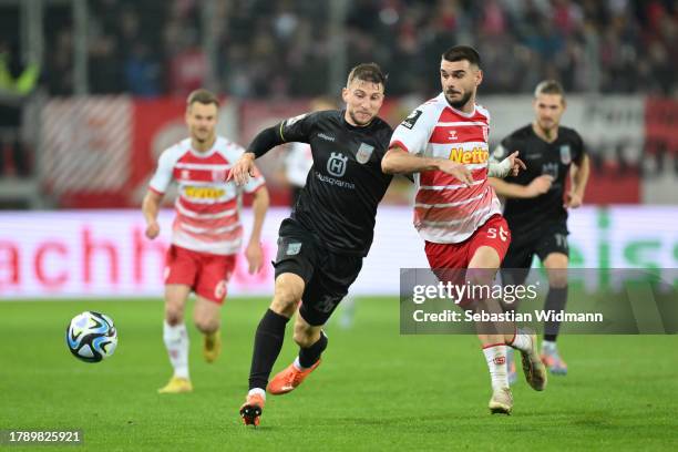 Philipp Maier of SSV Ulm 1846 and Rasim Bulic of SSV Jahn Regensburg compete for the ball during the 3. Liga match between SSV Jahn Regensburg and...