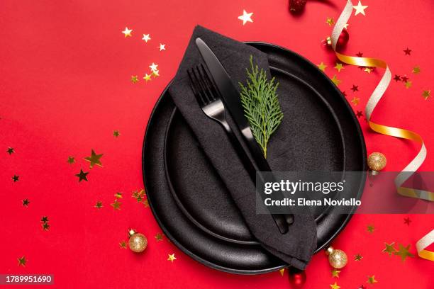 festive table setting black plate and christmas decor on red background, invitation dinner birthday party anniversary. top view - christmas table settings stock pictures, royalty-free photos & images