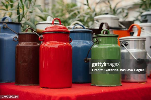 antique metal multi-colored bright milk cans at a flea market in europe - used milk cans stock pictures, royalty-free photos & images