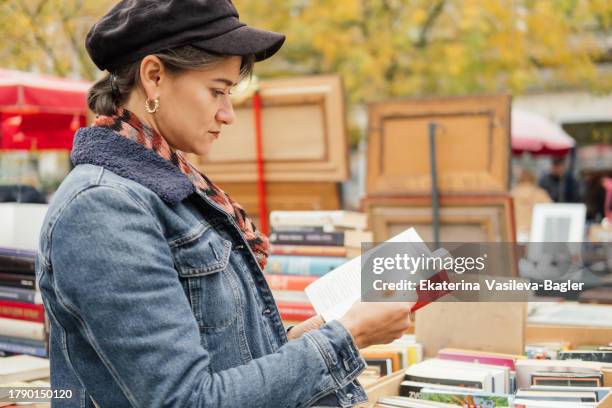 at the local flea market a woman is looking at vintage books. - second hand sale stock pictures, royalty-free photos & images