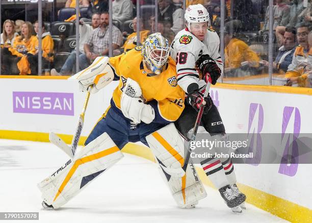 MacKenzie Entwistle of the Chicago Blackhawks battles behind the net against Kevin Lankinen of the Nashville Predators during an NHL game at...