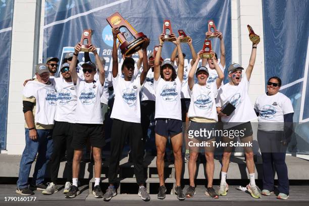 The Wingate University Bulldogs celebrate with their trophies after winning the Division II Men's Cross Country Championship held at Tom Rutledge...