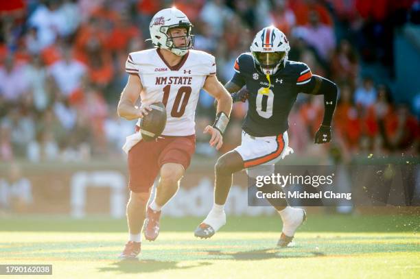Quarterback Diego Pavia of the New Mexico State Aggies scrambles with the ball while being chased by cornerback Keionte Scott of the Auburn Tigers...