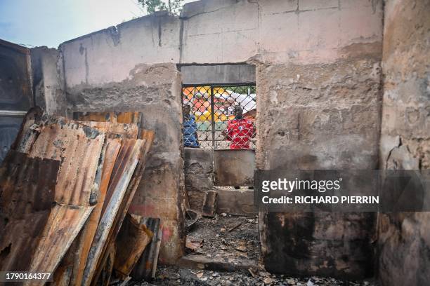 Men look through the window of a burnt-out house near Fontaine Hospital, now closed after an armed attack in the Cité Soleil district of...