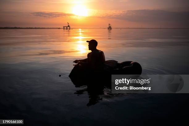 Fisherman paddles an inner tube on Lake Maracaibo in Cabimas, Zulia state, Venezuela, on Friday, Nov. 15, 2023. A decision by the US on Oct. 18 to...