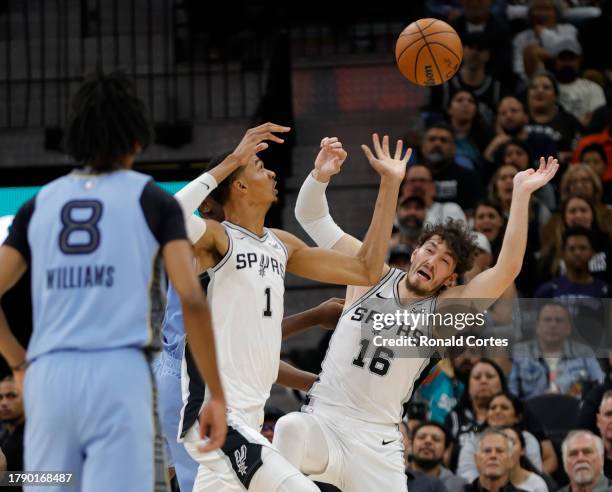 Victor Wembanyama and Cedi Osman of the San Antonio Spurs battle for a rebound against the Memphis Grizzlies in the second half at Frost Bank Center...