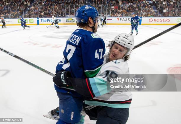 Noah Juulsen of the Vancouver Canucks checks Jared McCann of the Seattle Kraken during the third period of their NHL game at Rogers Arena on November...