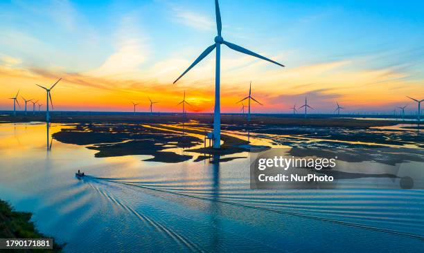 Wind turbine blades rotate in the tidal flat in Yancheng city, Jiangsu province, China, November 18, 2023.